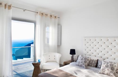 sypialnia z łóżkiem, krzesłem i oknem w obiekcie Belvedere Suites w mieście Firostefani