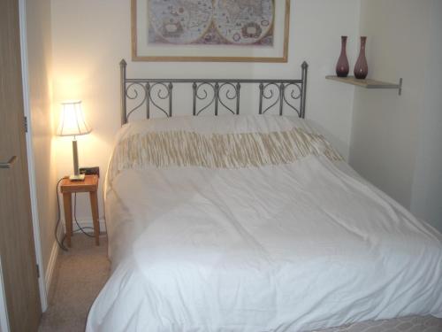 a bedroom with a white bed and a table with a lamp at Country House Ashdene in Highworth