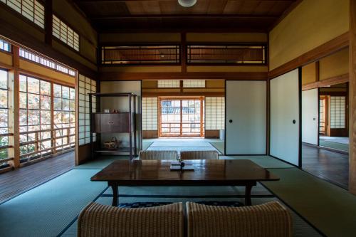 a room with a table and chairs and windows at NIPPONIA HOTEL Ozu Castle Town in Ōzu