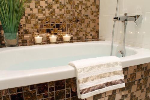 ein Bad mit einer Badewanne mit Kerzen in der Unterkunft Royal Prague Apartment Celakovskeho Sady in Prag
