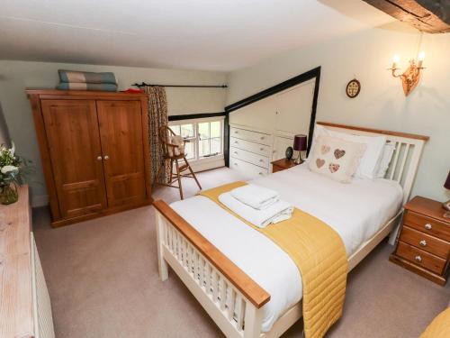 マーケット・レーゼンにあるClematis Cottageのベッドルーム1室(大型ベッド1台、木製キャビネット付)