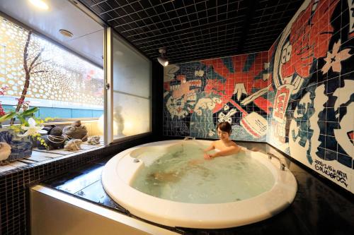 a woman sitting in a bath tub in a bathroom at Andon Ryokan in Tokyo
