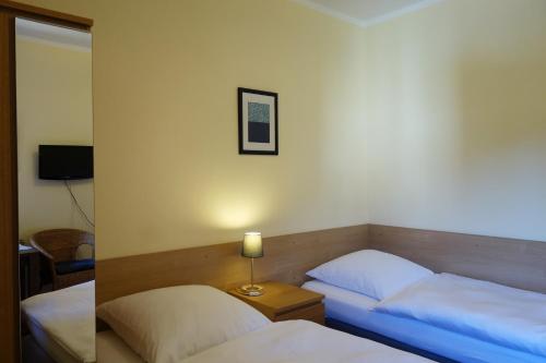 a bedroom with two beds and a lamp on a table at Pension am Helenenwall in Cologne
