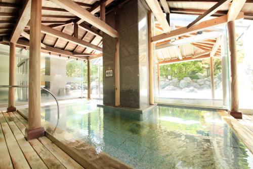 a swimming pool in a building with a large window at Hotel Mahoroba in Noboribetsu