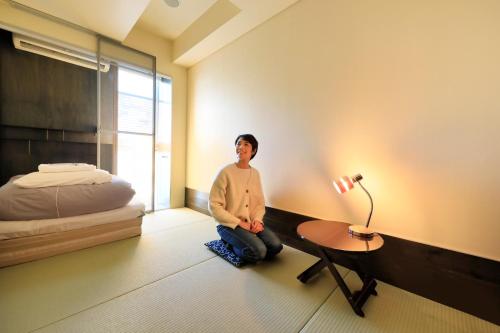 a man sitting on the floor in a room with a bed at Andon Ryokan in Tokyo