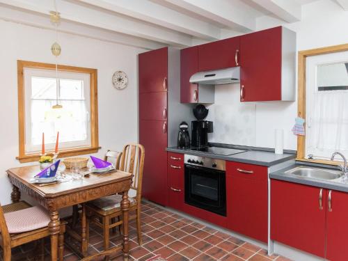 kuchnia z czerwonymi szafkami i stołem ze zlewem w obiekcie Apartment with garden near Monschau w mieście Schleiden
