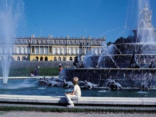 a child sitting in front of a fountain in front of a building at Bayerisches Refugium mit Sauna in Tittmoning