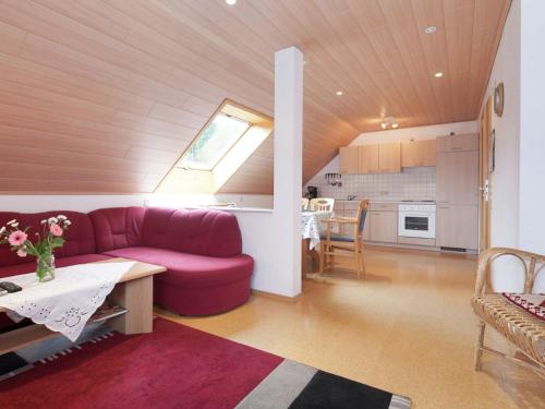 a living room with a red couch and a kitchen at Modern Apartment in Waldachtal near the Forest in Waldachtal