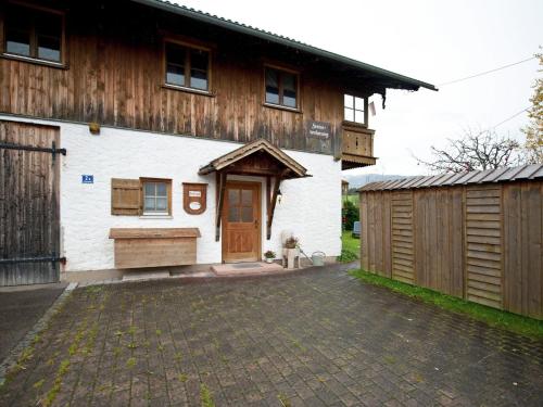 a white building with a wooden barn with a garage at Spacious apartment near the ski area in Steingaden