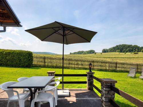 uma mesa e cadeiras com um guarda-sol num campo em Holiday home in Thuringia with garden em Mosbach