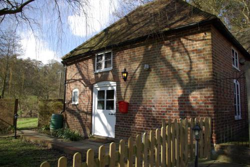 a brick house with a white door and a fence at Leeds Castle Holiday Cottages in Maidstone