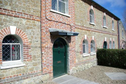 a brick building with a green door and windows at Leeds Castle Holiday Cottages in Maidstone