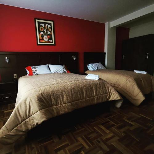 1 dormitorio con 2 camas y pared roja en Hostal Belisario en La Paz