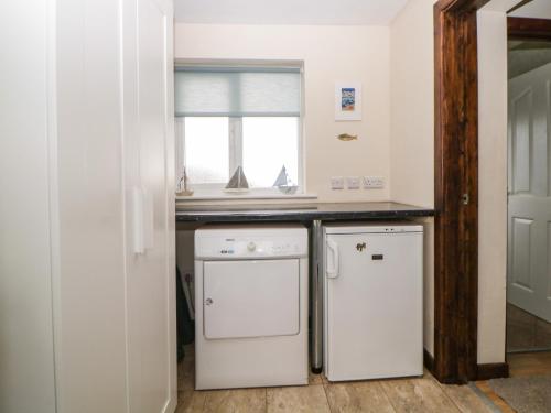 eine Küche mit Waschmaschine und Trockner und einem Fenster in der Unterkunft Broom Cottage in Sidmouth