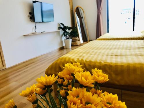 a bunch of yellow flowers in a room with a bed at TMS RUSTIC Beach in Quy Nhon