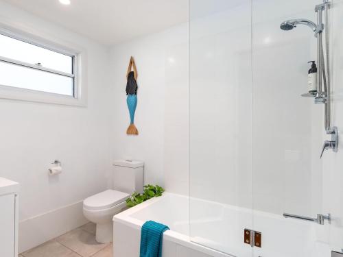a white bathroom with a toilet and a sink at Sirocco Cottage - pet-friendly Huskisson home in Huskisson