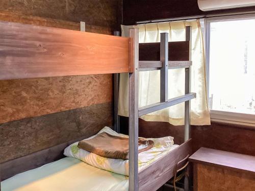 a bunk bed in a room with a window at Sesoko Island Guest House Kafuu Village in Motobu