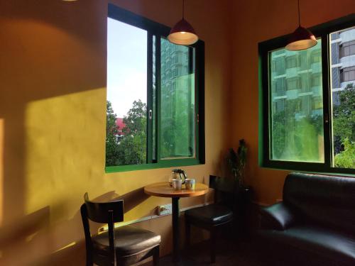 a small table and chairs in a room with two windows at Foshan Cuba Youth Hostel in Foshan