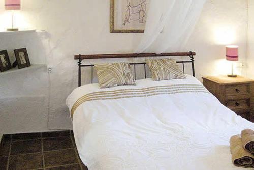 a bedroom with a white bed with two pillows at La Casita in Periana