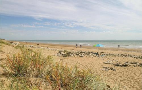 a group of people walking on a beach with an umbrella at Three-Bedroom Holiday Home In La Tranche Sur Mer in La Tranche-sur-Mer