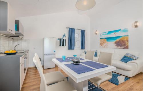 2 Bedroom Awesome Home In Kras في Kras: مطبخ وغرفة طعام مع طاولة وكراسي بيضاء
