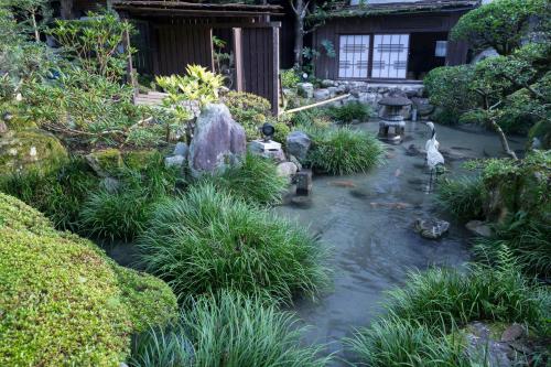 a garden with a pond with rocks and plants at Kakureisen in Saga