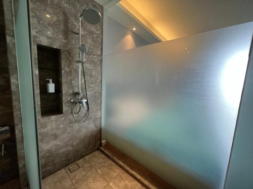 a shower stall in a bathroom with a stone wall at The Shore Melaka in Melaka