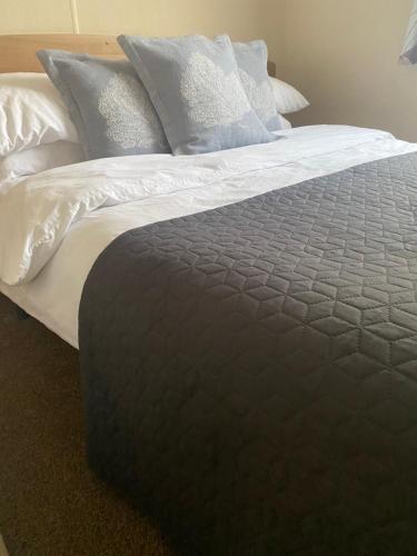 a large bed with white sheets and pillows at KellysHolidayHomes Atlas 3 bedrooms caravan in Weeley