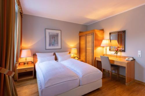 a bedroom with a white bed and a desk and a desk at Hotel Halm Konstanz in Konstanz