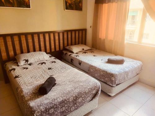 two twin beds in a room with a window at Beach view apartment from balcony in Banting