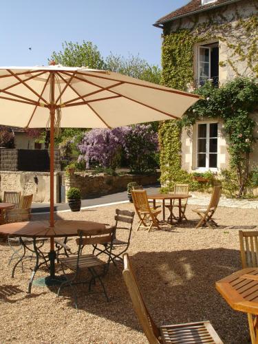 a patio with tables and chairs and an umbrella at Le Relais du Lyon d'Or in Angles-sur-lʼAnglin