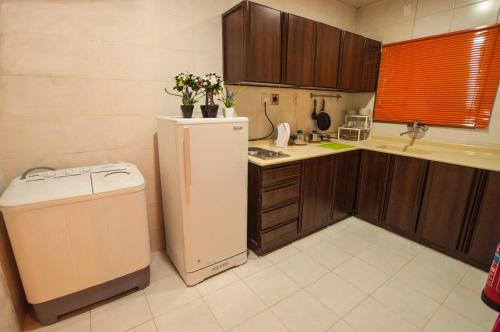 una pequeña cocina con nevera y lavadora en City Suites, en Al Khobar