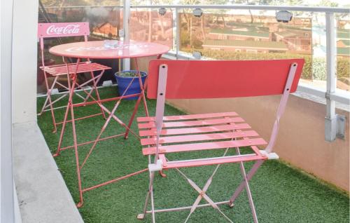 une chaise rouge assise à côté d'une table sur un balcon dans l'établissement Amazing Apartment In Grandcamp Maisy, à Grandcamp-Maisy