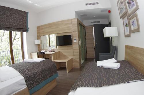 a hotel room with two beds and a desk at Hotel Therapia in Pécs
