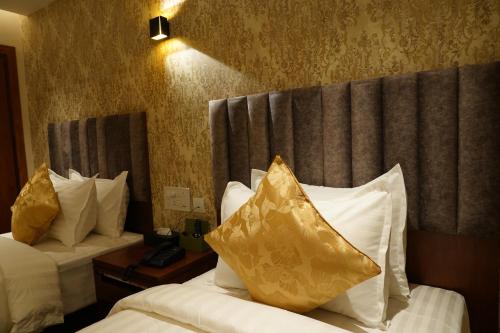 a hotel room with two beds with yellow pillows at The Kings Park Grand-Near US Consulate in Chennai