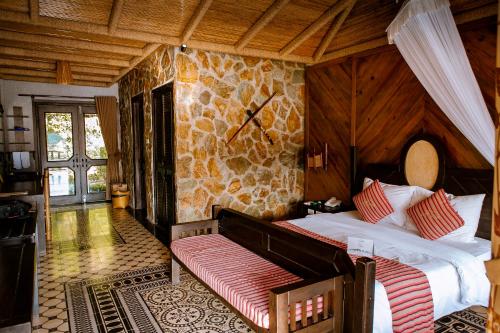 a bedroom with two beds and a stone wall at Mai Chau Ecolodge in Mai Chau