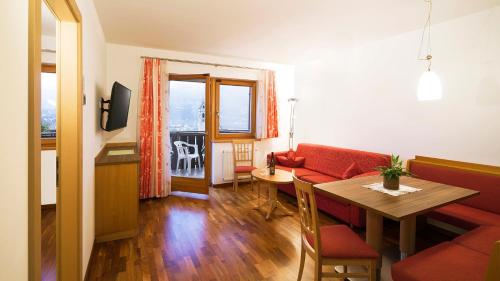 - un salon avec un canapé rouge et une table dans l'établissement Hotel Sonnenhof, à Marlengo