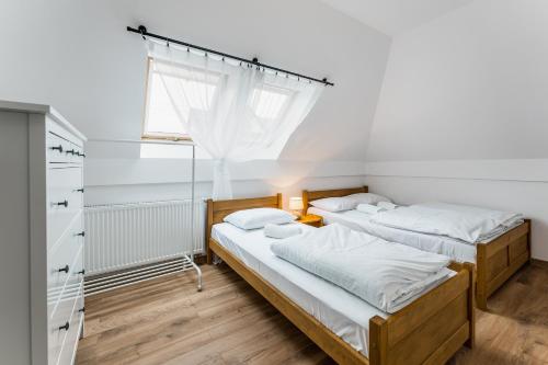two beds in a room with a window at Apartamenty na Rycerskiej in Czorsztyn