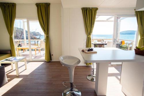 a living room with a table and a view of the ocean at Camping Europa in Capoliveri