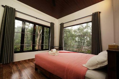 Un dormitorio con una cama y dos grandes ventanales. en Entire Villa at the Heart of the Wayanad Forest., en Kutta