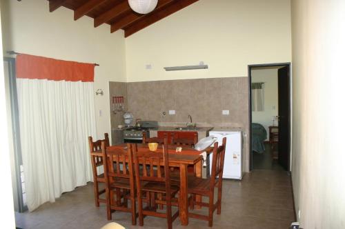 cocina y comedor con mesa de madera y sillas en El Rincón del Molle en Merlo