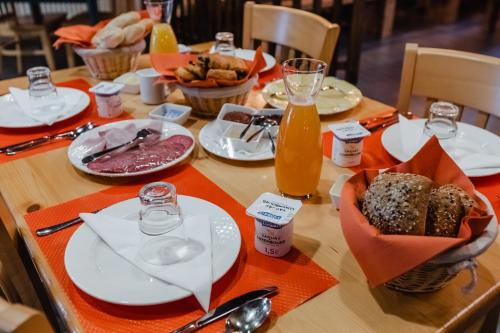 a wooden table with plates of food and orange napkins at Hotel Cornelyshaff in Heinerscheid