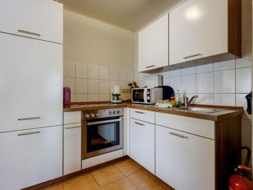 cocina con armarios blancos y fogones en Luxury Apartment in Schleusingen Thuringia near Lake, en Schleusingen