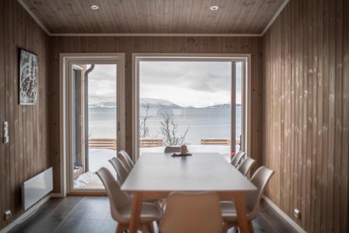 a dining room with a table and chairs and a large window at Lyngen Alps Panorama in Russelv