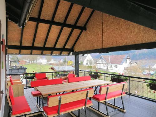 a large deck with a wooden table and red chairs at Chic Holiday Home in Liesen with Garden in Hallenberg