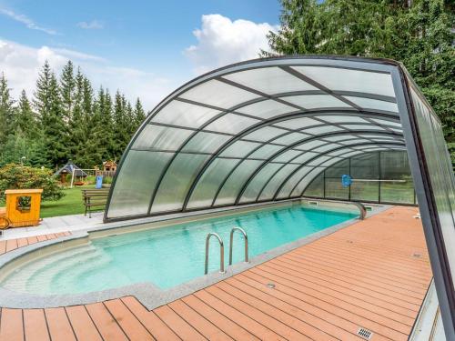 a swimming pool with a retractable canopy over it at Holiday home with shared pool in J gersgr n in Bad Reiboldsgrün