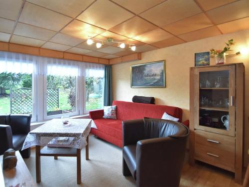 un soggiorno con divano rosso e tavolo di Idyllic holiday home in Neinstedt near forest a Thale
