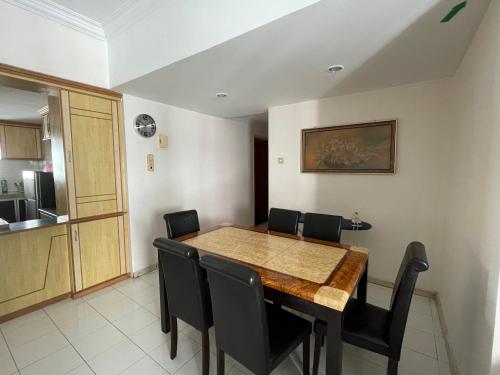 a dining room with a wooden table and black chairs at Porte Bleue Pantai Puteri in Melaka