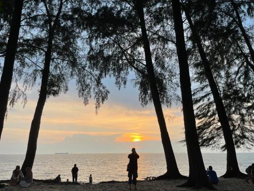 a group of people on the beach at sunset at Porte Bleue Pantai Puteri in Melaka