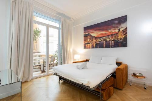 1 dormitorio con cama y ventana grande en Promenade, 2pièces chic et clim avec terrasse en Niza
